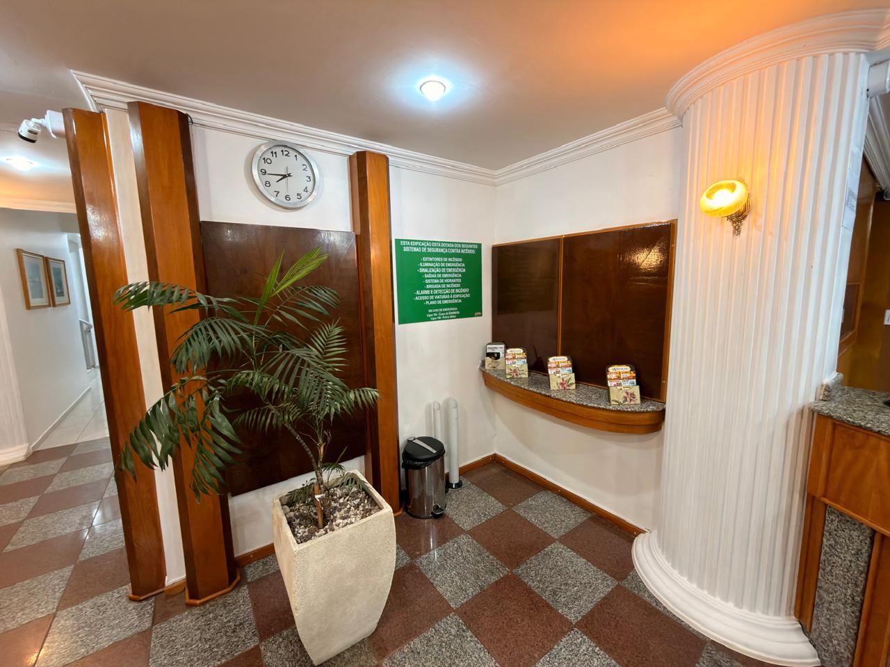 Detalhe do hall do Hotel Mello com planta ornamental, relógio e murais