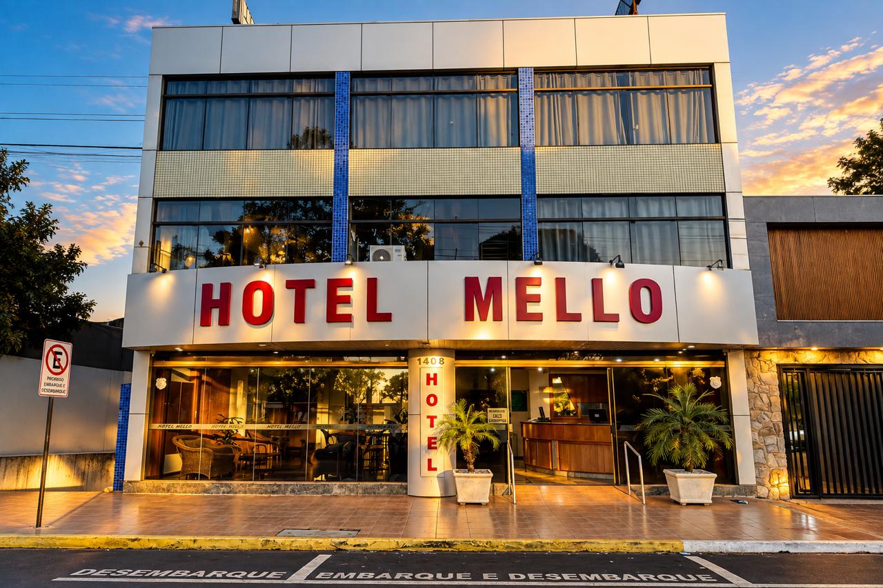 Fachada iluminada do Hotel Mello ao entardecer